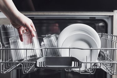 Open dishwasher with clean cutlery, glasses, dishes inside in the home kitchen