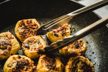 asian woman pan frying tofu with meat stuffing (酿豆腐)-traditional Cantonese food