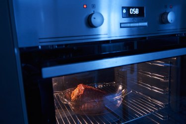A tender piece of pork roasting in the oven, sizzling in its juices, creating a golden crust and emitting a tantalizing aroma. Inside, the pink flesh is seasoned with spices