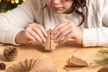 girl makes Christmas tree decorations out of paper with her own hands. step 4