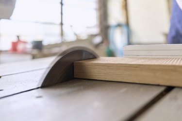 close-up of a circular saw on a workbench in the workshop cutting a wooden board, side view