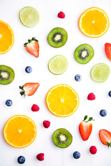 Various berries and cut-up fruit on white background
