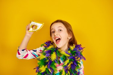 A joyful teenager girl wearing a colorful Brazil carnival mask