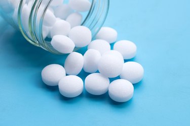 Open jar of naphthalene mothballs on blue background
