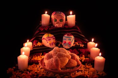 Mexican day of the dead altar with bread and sugar skulls on dark background