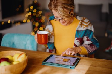 Mature woman using digital tablet for online Christmas shopping