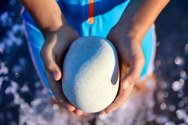 smooth gray stone in the hands of a small child on the beach