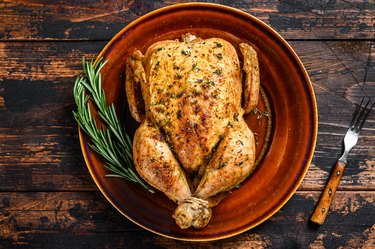 Delicious baked chicken on wooden table. Dark background. Top view