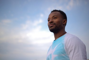 young spiritual man on blue cloudy sky tie and dye t-shirt