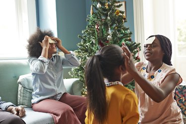 Sisters sticking notes on forehead at home