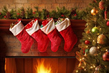 Christmas stockings hanging from a mantelpiece above glowing fireplace