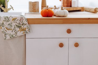 A kitchen counter with a white cabinet and a towel with a floral design