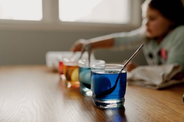 Little Girl Checking on the Progress of her Easter eggs in Glasses of Dye