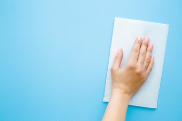 Hand wiping blue wall