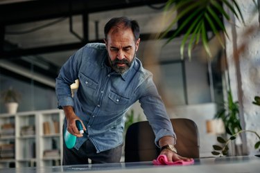 Businessman disinfecting his desk in the office