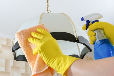 Wiping dust from the chandelier with a rag and detergent