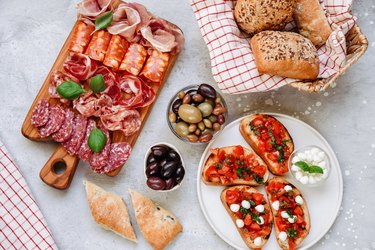 Food antipasto prosciutto ham, salami, olives and bread and Tomato and basil bruschetta Charcuterie board. Two glasses of white wine or prosecco