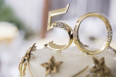 Number 50 in golden plastic attached to the top of a wedding anniversary cake
