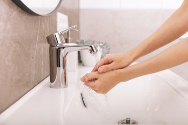 Washing hands under the flowing water tap. Washing hands rubbing with soap for corona virus prevention, hygiene to stop spreading corona virus in or public wash room. Hygiene concept hand detail