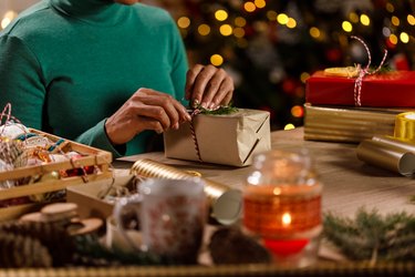 Midsection of woman decorating a Christmas present she wrapped in brown paper