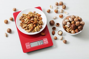 mix of different nuts on kitchen scale on a white table