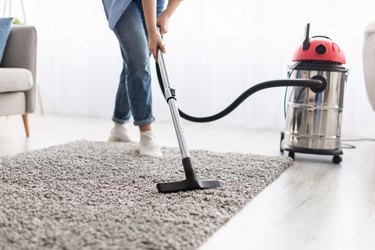 Woman cleaning carpet with vacuum cleaner