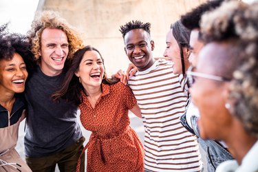 Young happy people laughing together - Multiracial friends group having fun on city street - Diverse culture students portrait celebrating outside - Friendship, community, youth, university concept