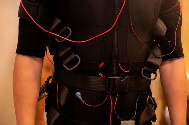 Close-up of fit man in black full body suit for ems training and muscular electrode technology.
