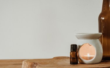 Candle warmer and glass bottle on wooden desk. Copy space.