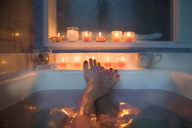 Feet in bath, candles in background