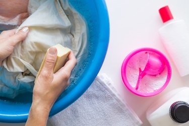 Housewife washing clothes with different detergents in the bowl. Dry cleaning concept. Clothes care. Chores of maid. Regular washing.