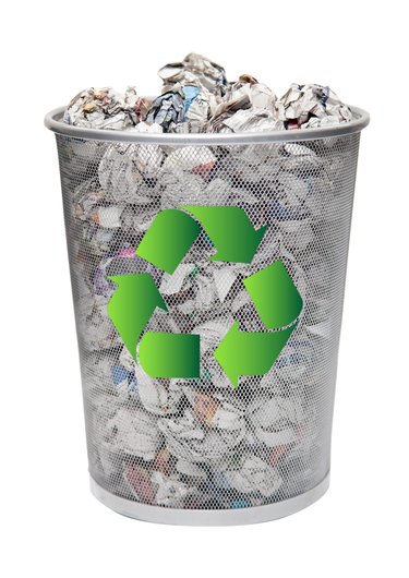 Recycling bin full of crumpled papers over white background