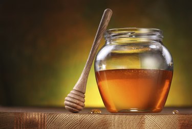Pot of honey and wooden stick.