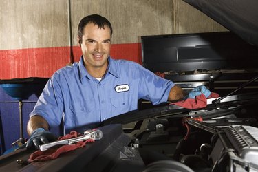 Auto mechanic posing next to car