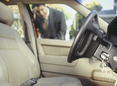 Businessman looking through window at keys locked in car