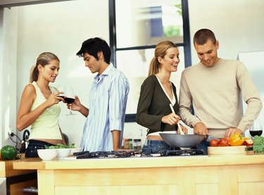two young couple drinking and preparing food in the kitchen