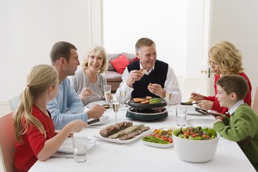 Family cooking vegetables on raclette grill