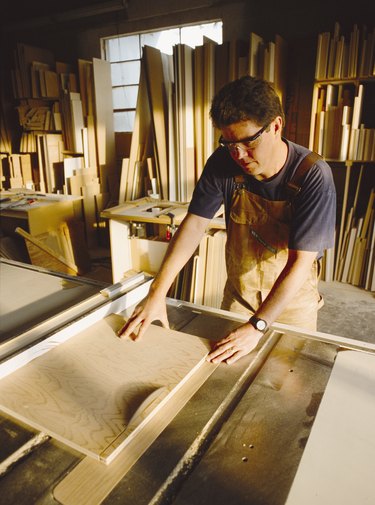 a carpenter cuts a board with a saw