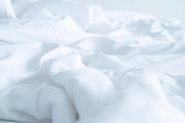 Close up messy Soft pillows on comfortable crumpled linen bed sheet in the hotel.