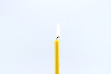 Close-Up Of Burning Candle Against White Background
