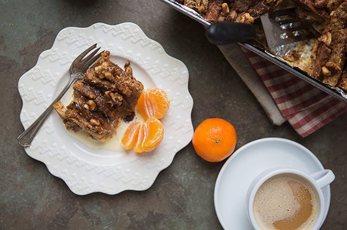 Plate of cinnamon roll French toast breakfast bake with tangerine half.