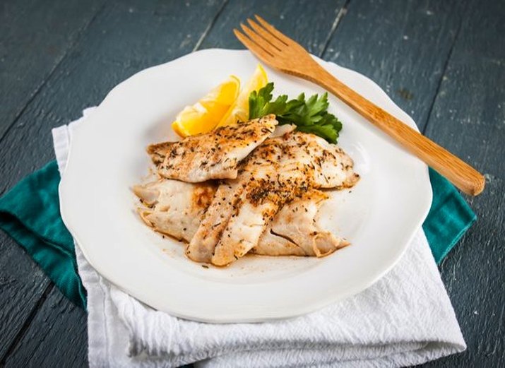 Dish of grilled red snapper with lemon wedge.