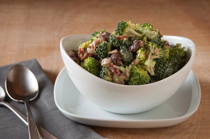 Broccoli bacon raisin salad in white bowl.
