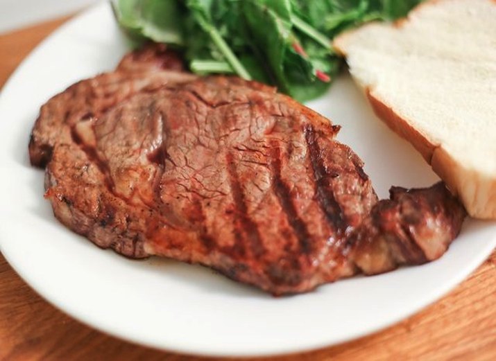 Plate of grilled rib-eye steak, salad and toast.