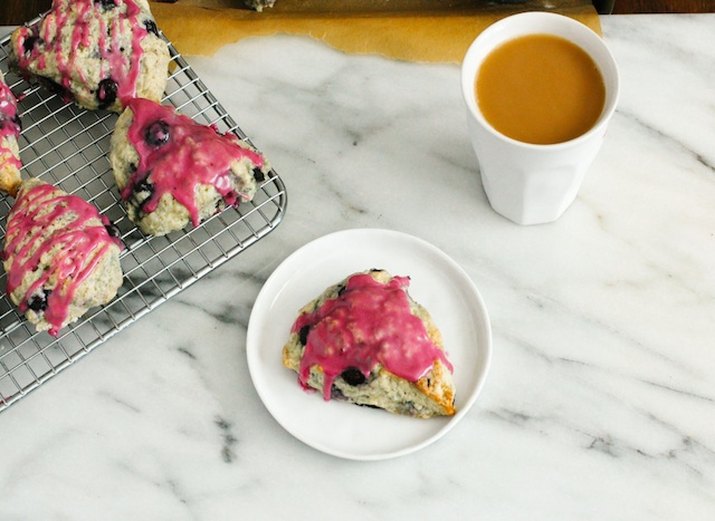 Plate and wire rack of blueberry-glazed scones with a cup of coffee.