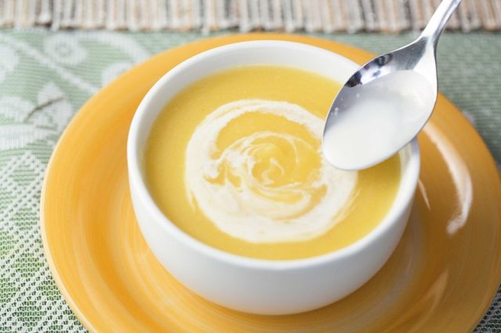 A bowl of orange-tinted pumpkin soup topped with a dollop of cream.