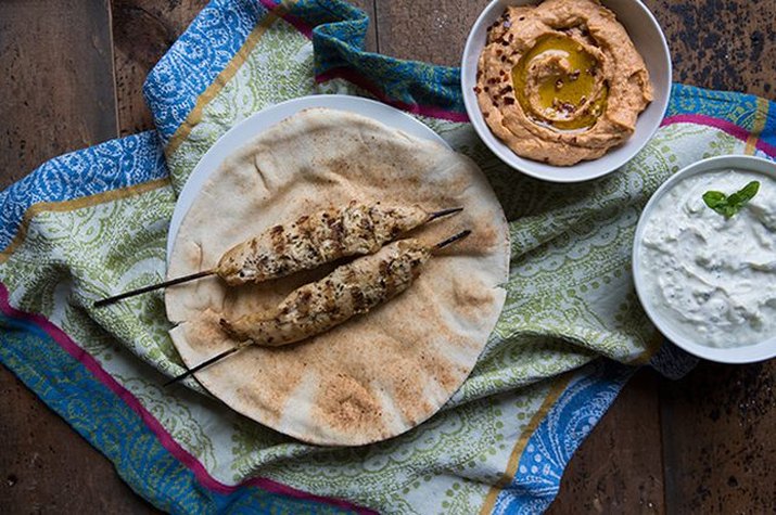 Chicken souvlaki served with tomatoes, cucumbers, onions and pita bread.