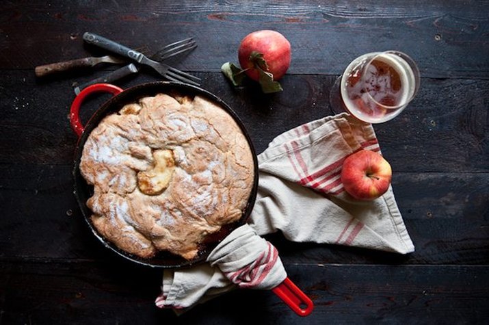 A cast iron cobbler next to a glass of hard apple cider