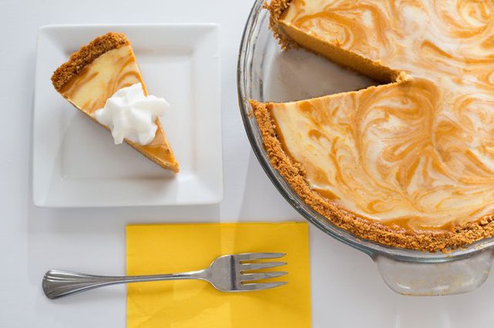A swirly pumpkin cheesecake with whipped cream on top.
