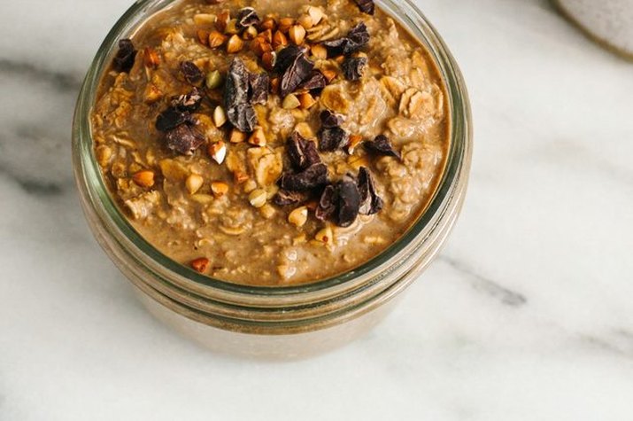 A small mason jar filled with chocolate protein overnight oats.